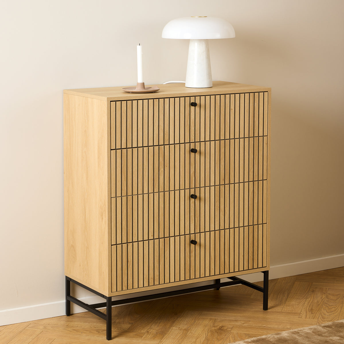 Bambouz-kommode 81x100 ved en beige væg med en hvid lampe og et lys på parketgulvet i fiskebensmønster – en kommode til soveværelset