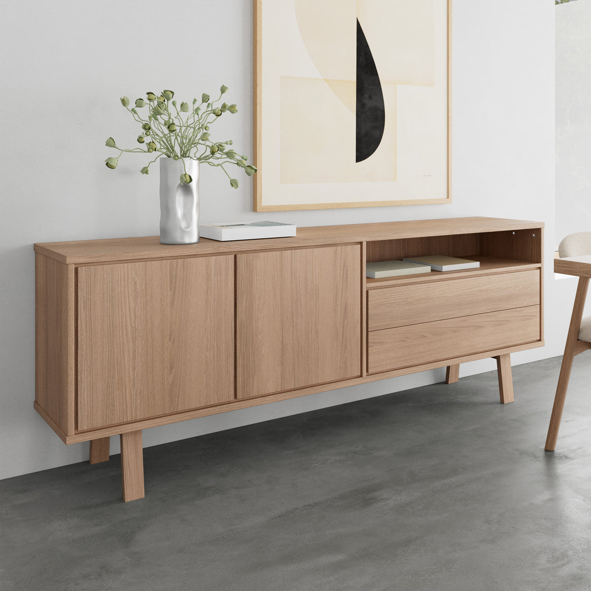 Lurisse-kommode 200x75 i bleget eg under billedet ved en grå væg, med en vase og bøger – en kommode til stuen