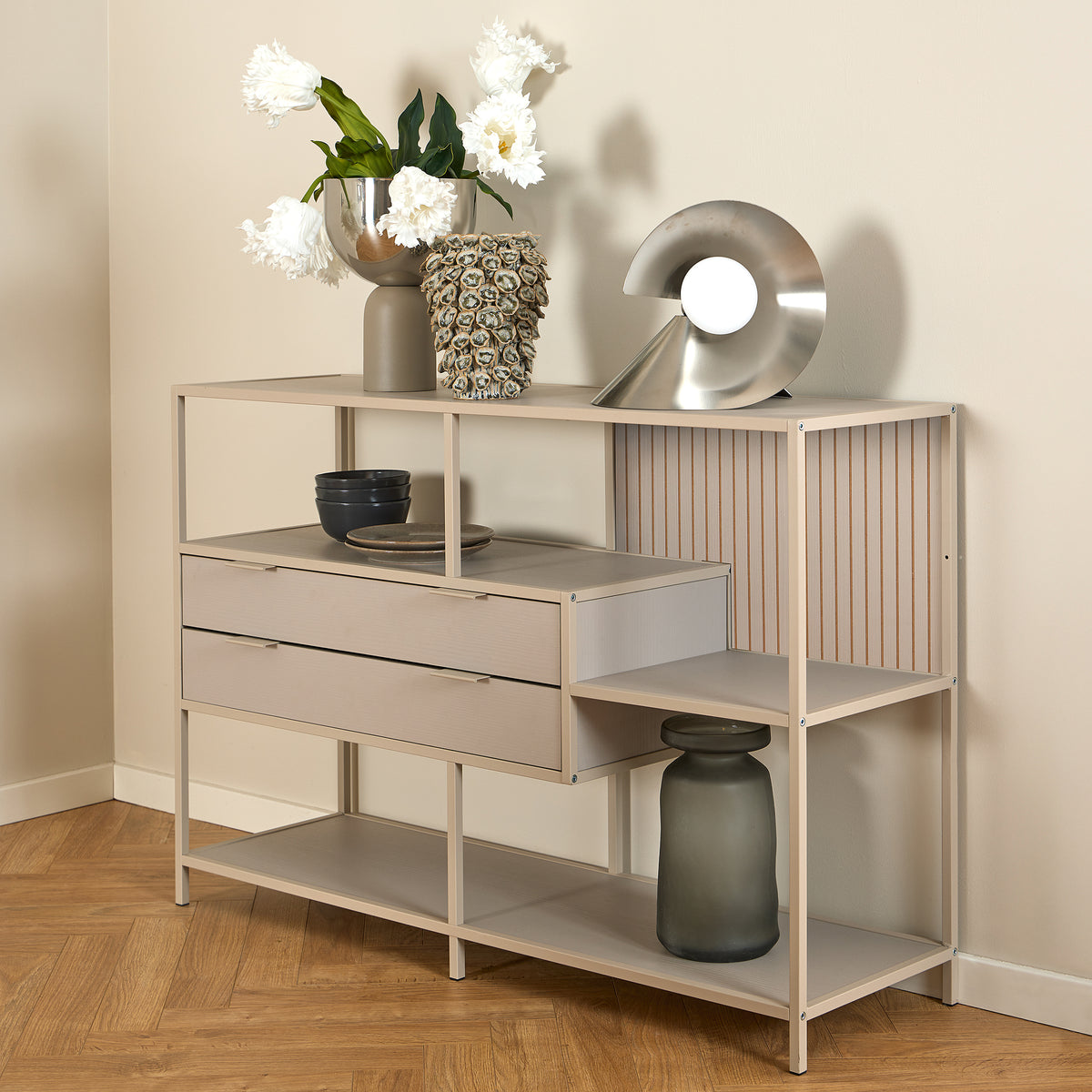 Lavt reol Skeleto 114x78, grå melamin med hvide blomster i en vase og en sølvfarvet lampe på hylden