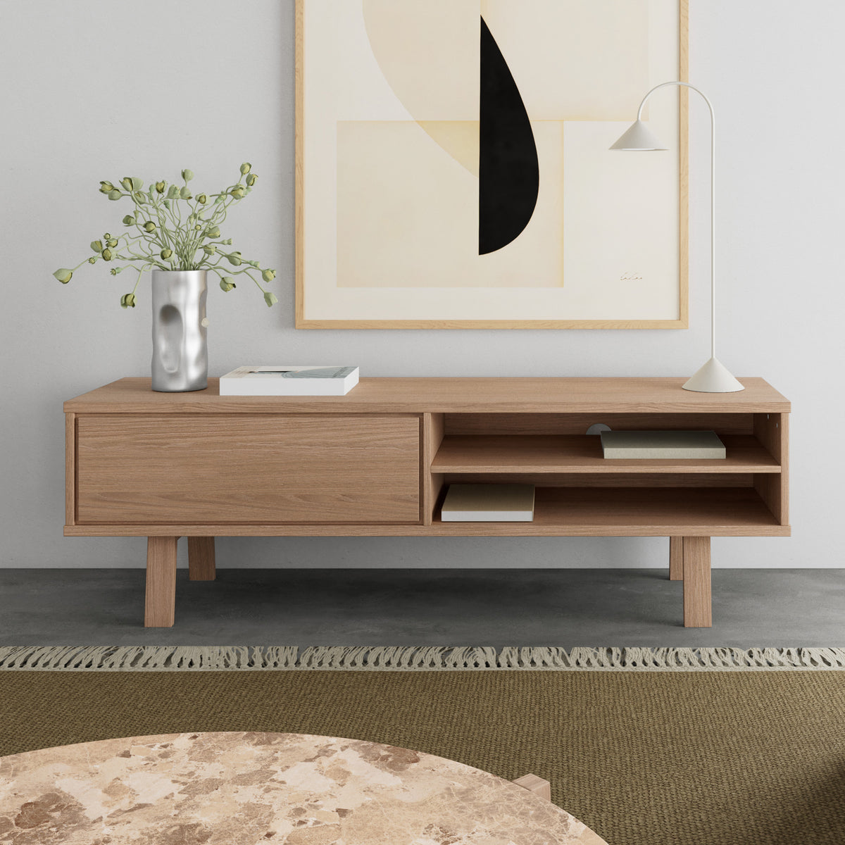 Lurisse TV-bord 160x50 i bleget eg med motiv, med lampe og vase, foran et marmorbord i stuen